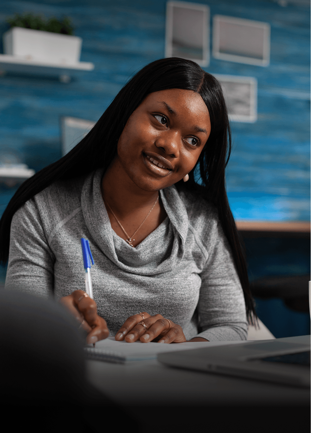 A female mentor writing in a notebook and smiling
