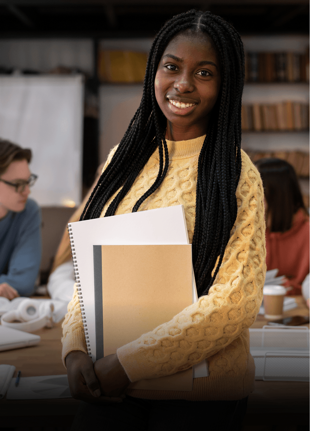 A female student smiling and holding notebooks